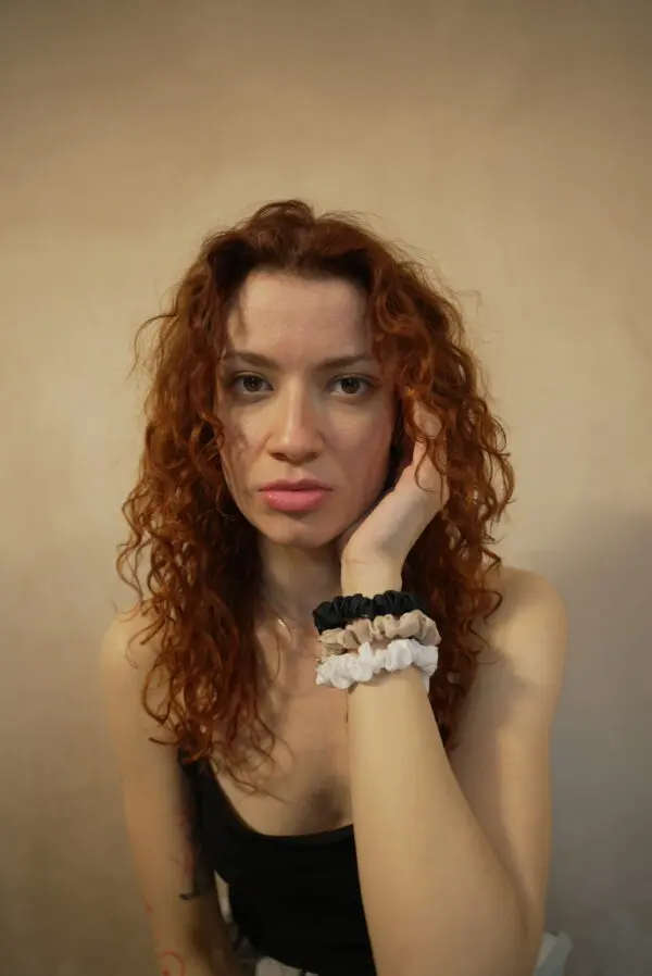 Woman with curls wearing 3 slim 100% bamboo scrunchies around her wrist
